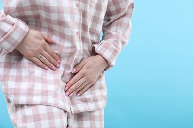 Photo of Woman suffering from cystitis symptoms on light blue background, closeup. Space for text
