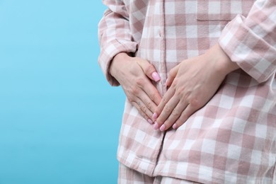 Photo of Woman suffering from cystitis symptoms on light blue background, closeup. Space for text