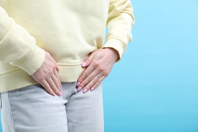 Photo of Woman suffering from cystitis symptoms on light blue background, closeup. Space for text