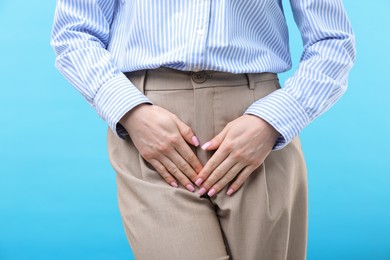 Photo of Woman suffering from cystitis symptoms on light blue background, closeup