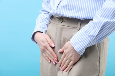 Photo of Woman suffering from cystitis symptoms on light blue background, closeup. Space for text