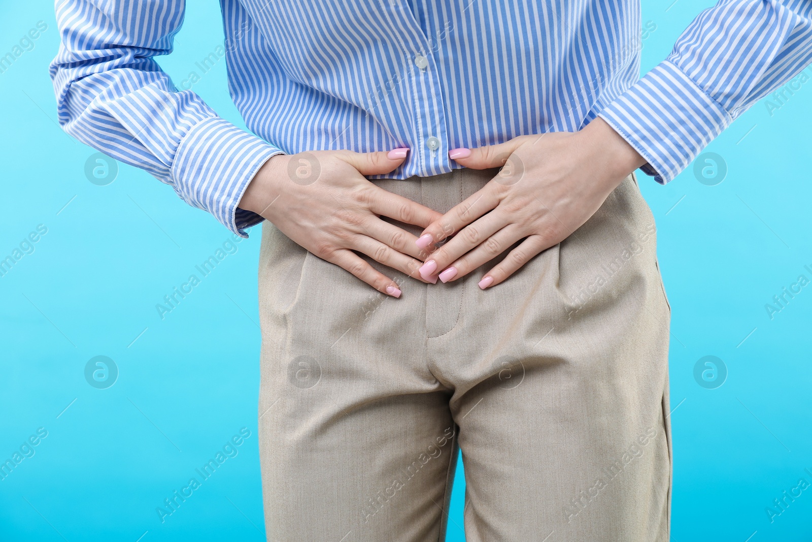 Photo of Woman suffering from cystitis symptoms on light blue background, closeup