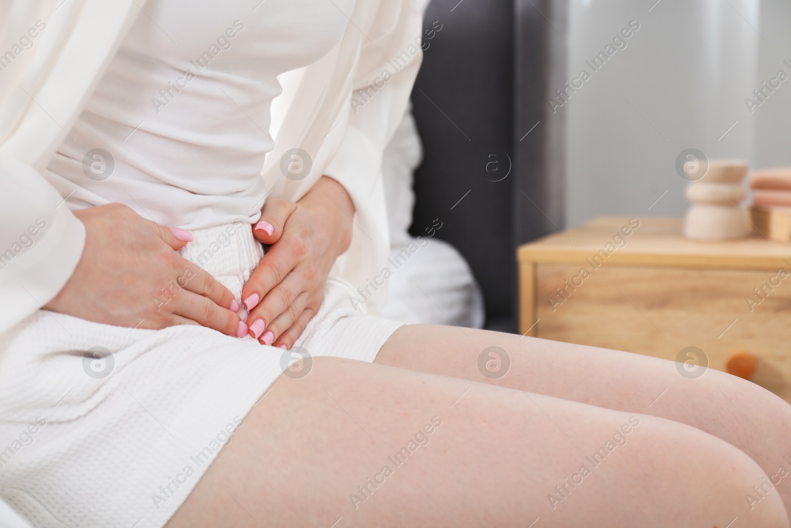 Photo of Woman suffering from cystitis symptoms on bed at home, closeup