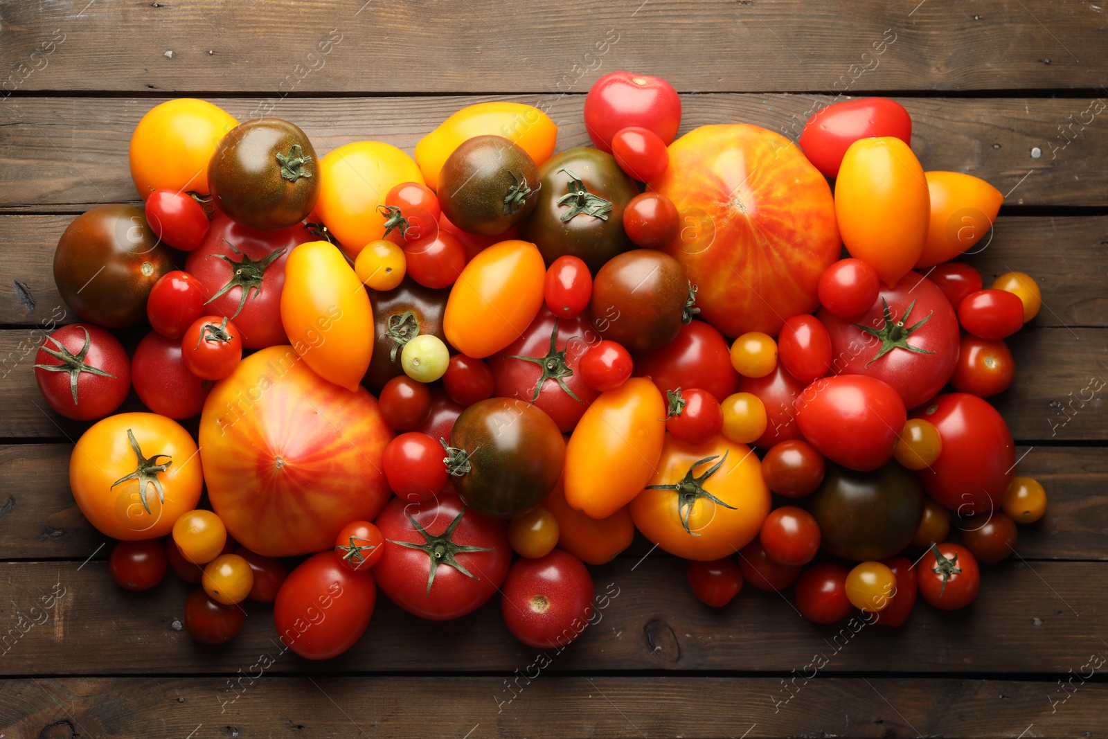 Many different ripe tomatoes on wooden table, flat lay Photo of Many different ripe tomatoes on wooden table, flat lay