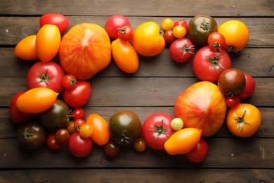 Photo of Frame of many different ripe tomatoes on wooden table, flat lay. Space for text
