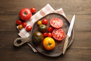 Photo of Different ripe tomatoes and knife on wooden table, flat lay