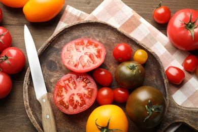 Photo of Different ripe tomatoes and knife on wooden table, flat lay