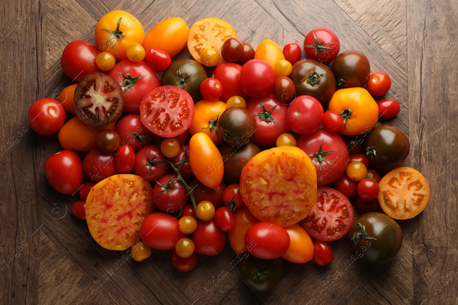 Photo of Many different ripe tomatoes on wooden table, flat lay