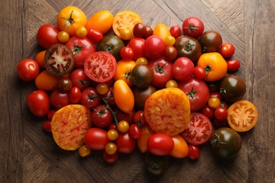 Photo of Many different ripe tomatoes on wooden table, flat lay