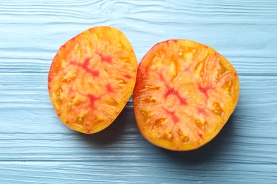 Photo of Pieces of ripe yellow tomato on light blue wooden table, closeup