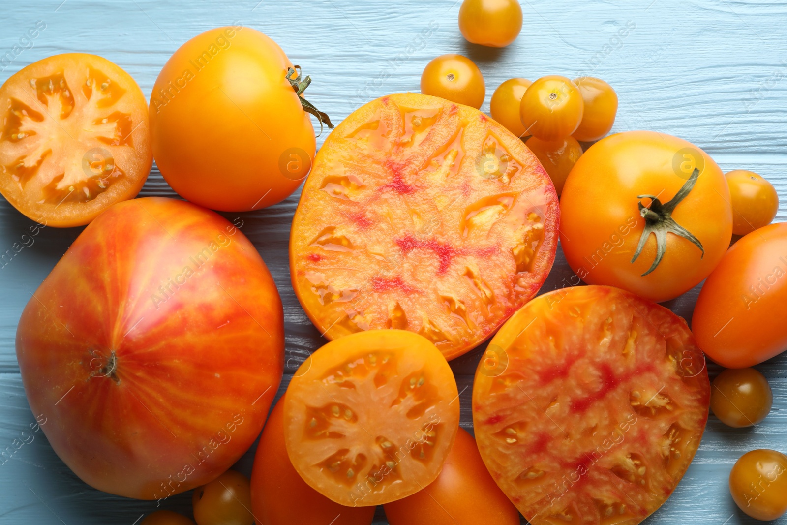 Many ripe yellow tomatoes on light blue wooden table, flat lay Photo of Many ripe yellow tomatoes on light blue wooden table, flat lay