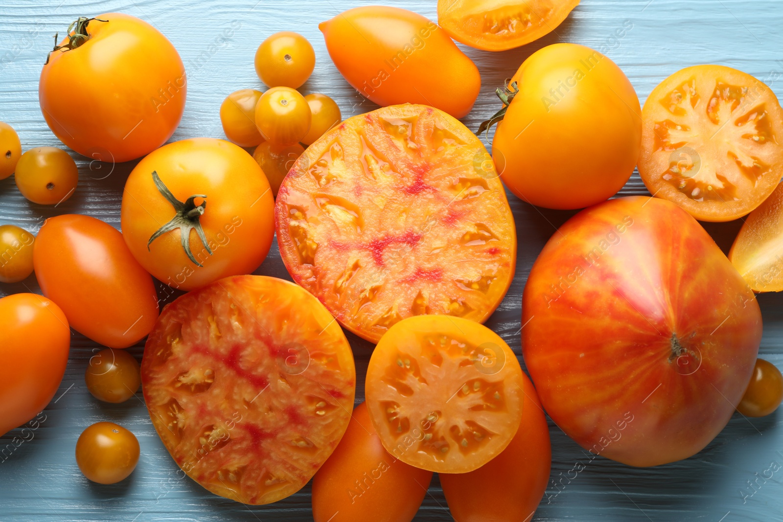 Many ripe yellow tomatoes on light blue wooden table, flat lay Photo of Many ripe yellow tomatoes on light blue wooden table, flat lay