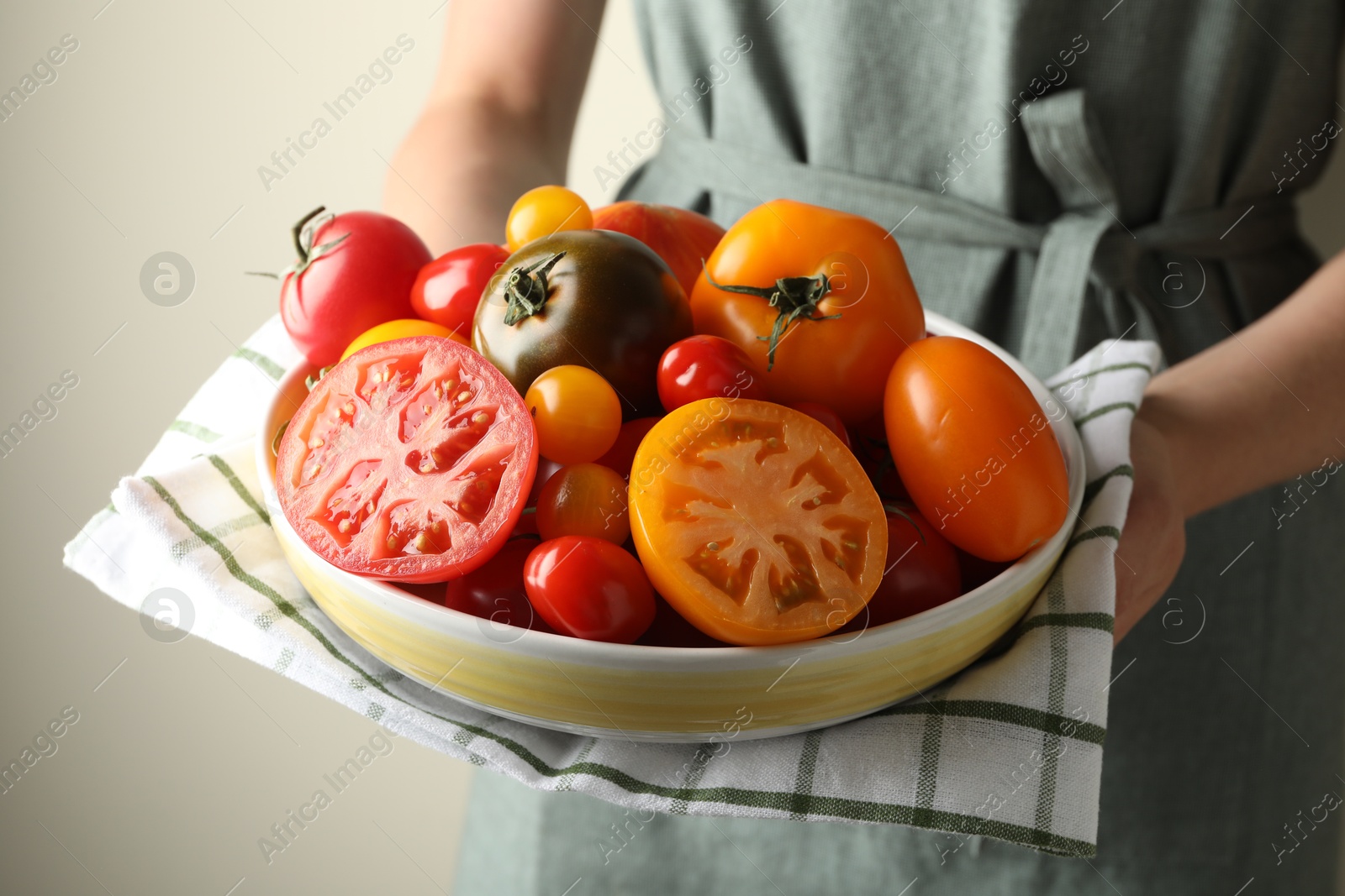 Woman with ripe tomatoes in bowl on light background, closeup Photo of Woman with ripe tomatoes in bowl on light background, closeup