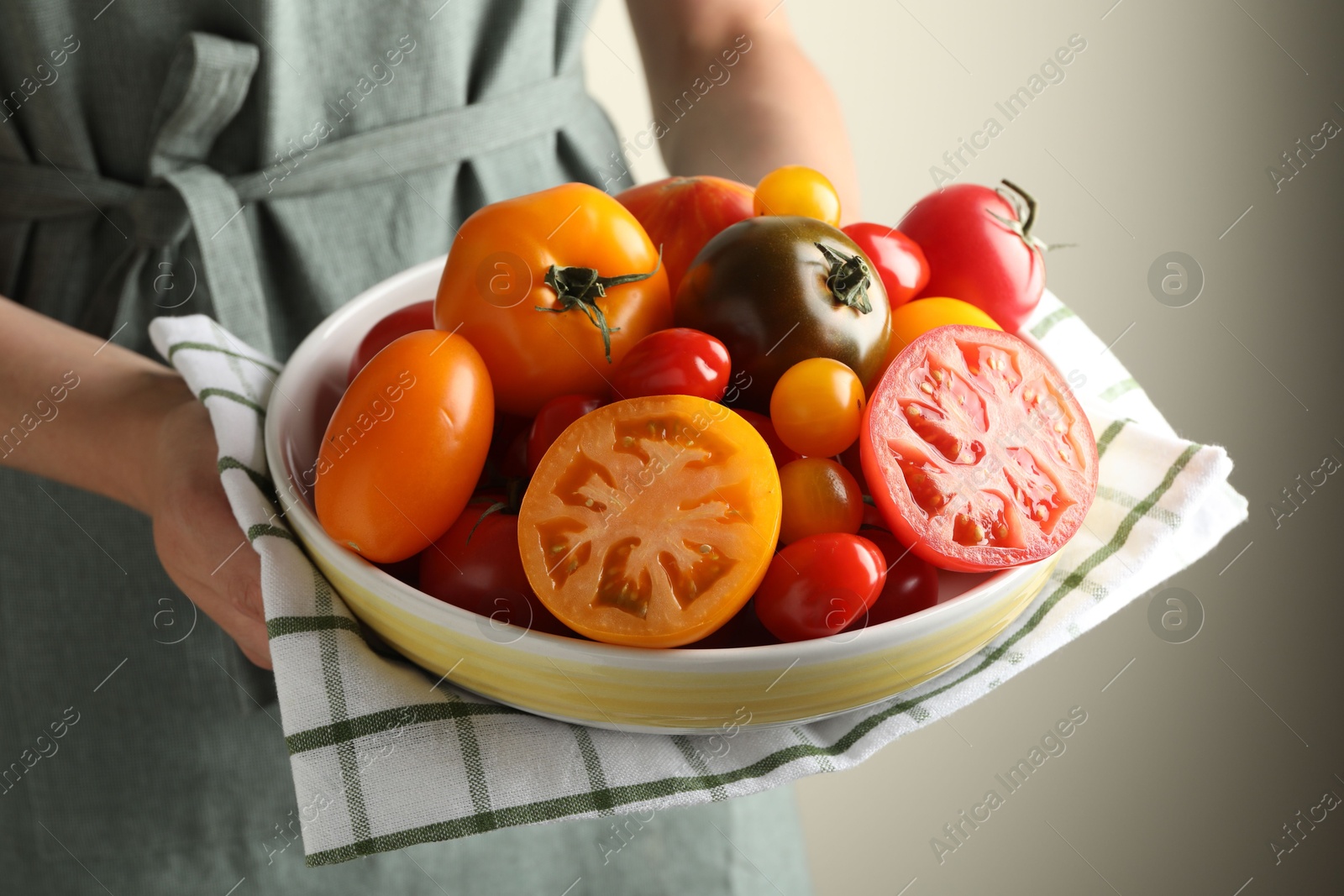 Woman with ripe tomatoes in bowl on light background, closeup Photo of Woman with ripe tomatoes in bowl on light background, closeup