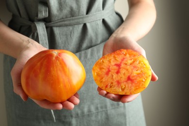 Photo of Woman with whole and cut yellow tomatoes on light background, closeup