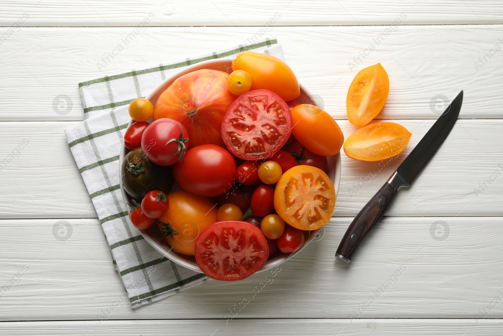 Photo of Different ripe tomatoes and knife on white wooden table, flat lay