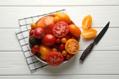 Photo of Different ripe tomatoes and knife on white wooden table, flat lay