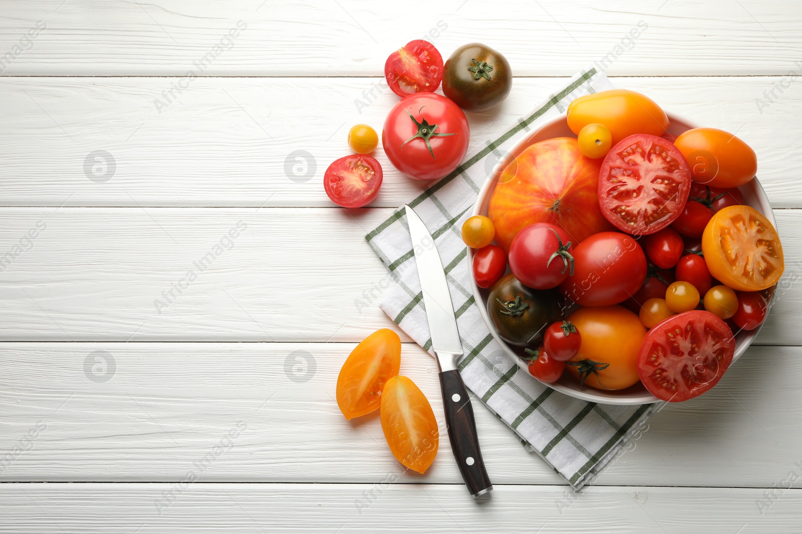 Different ripe tomatoes and knife on white wooden table, flat lay. Space for text Photo of Different ripe tomatoes and knife on white wooden table, flat lay. Space for text