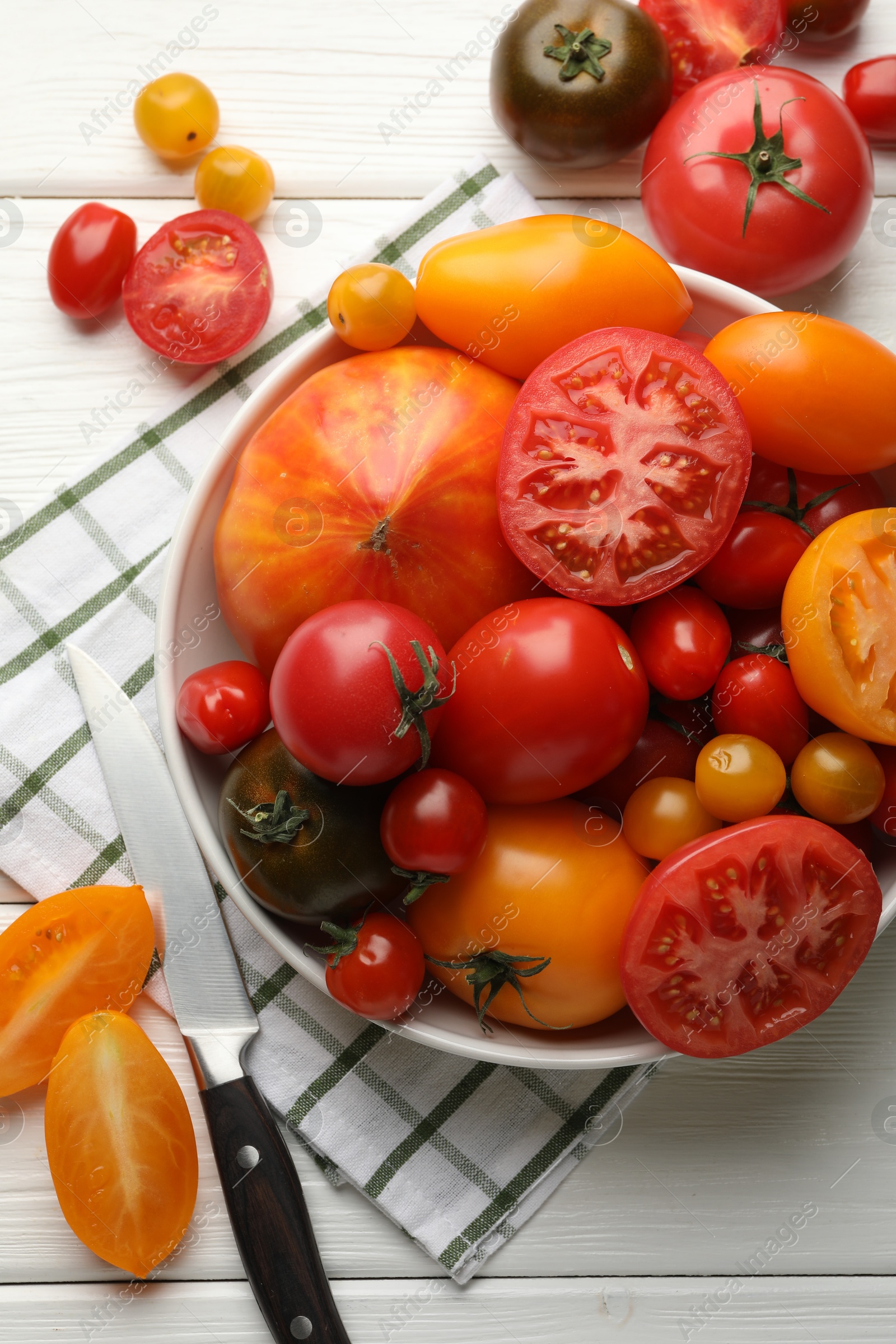 Different ripe tomatoes and knife on white wooden table, flat lay Photo of Different ripe tomatoes and knife on white wooden table, flat lay