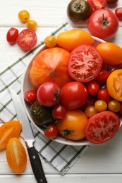 Photo of Different ripe tomatoes and knife on white wooden table, flat lay
