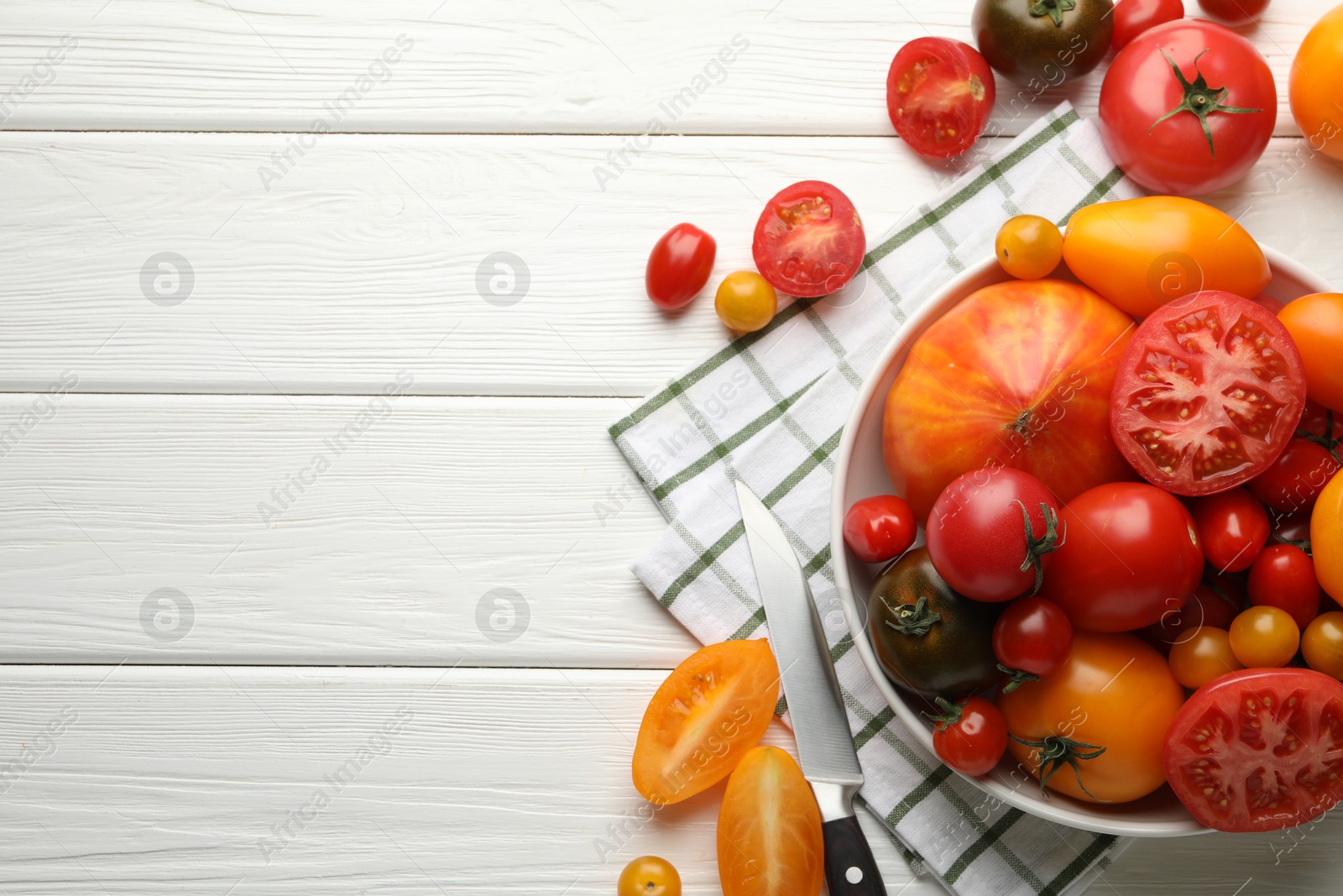 Different ripe tomatoes and knife on white wooden table, flat lay. Space for text Photo of Different ripe tomatoes and knife on white wooden table, flat lay. Space for text