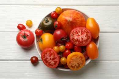 Photo of Many different ripe tomatoes on white wooden table, top view