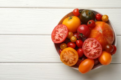 Photo of Many different ripe tomatoes on white wooden table, top view. Space for text