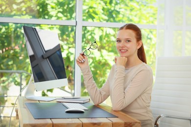 Photo of Teenage girl using computer at wooden desk indoors. Home workplace