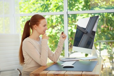 Photo of Teenage girl using computer at wooden desk indoors. Home workplace