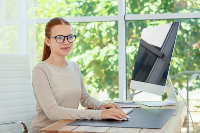Photo of Teenage girl using computer at wooden desk indoors. Home workplace