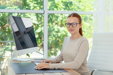 Photo of Teenage girl using computer at wooden desk indoors. Home workplace