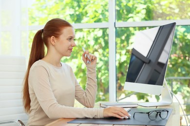 Photo of Teenage girl using computer at wooden desk indoors. Home workplace