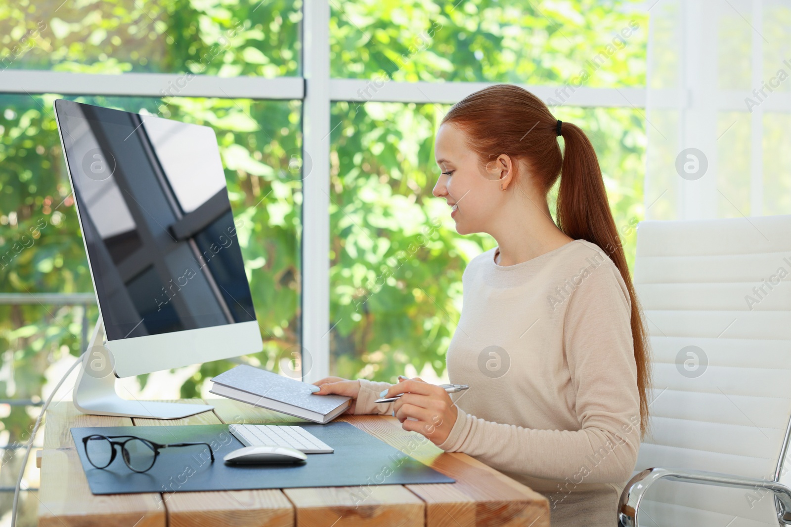 Photo of Teenage girl using computer at wooden desk indoors. Home workplace