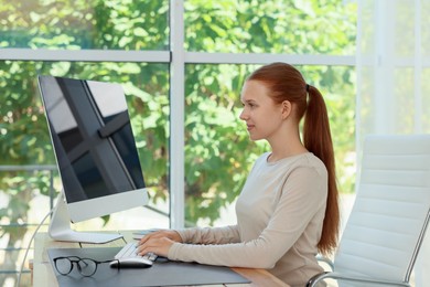 Photo of Teenage girl using computer at wooden desk indoors. Home workplace