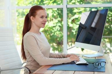 Photo of Teenage girl using computer at wooden desk indoors. Home workplace