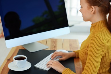 Photo of Teenage girl using computer at wooden desk indoors. Home workplace