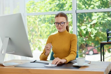 Photo of Teenage girl using computer at wooden desk indoors. Home workplace