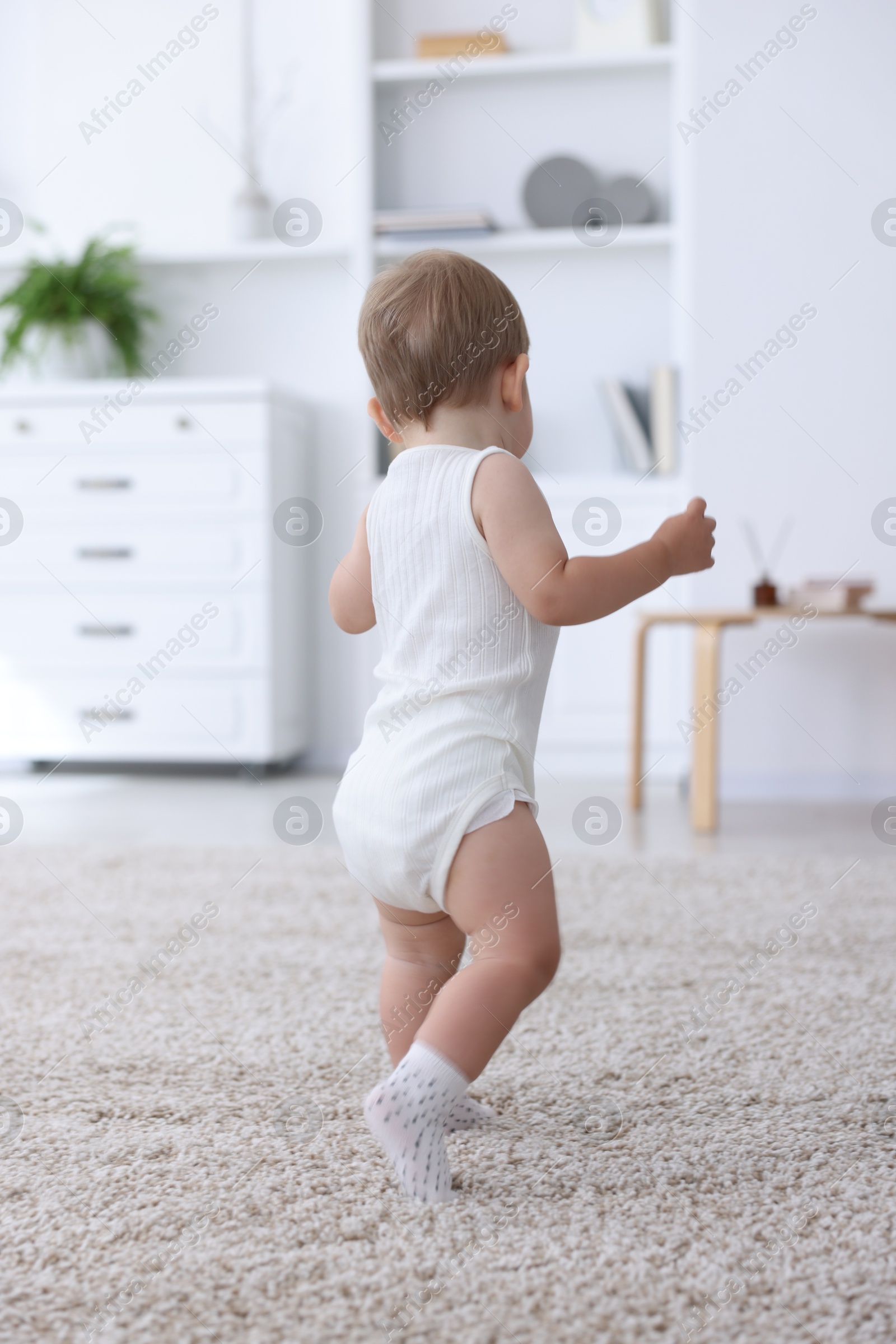 Photo of Cute little baby in onesie at home