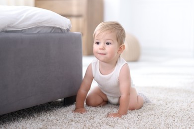 Photo of Cute little baby near bed at home