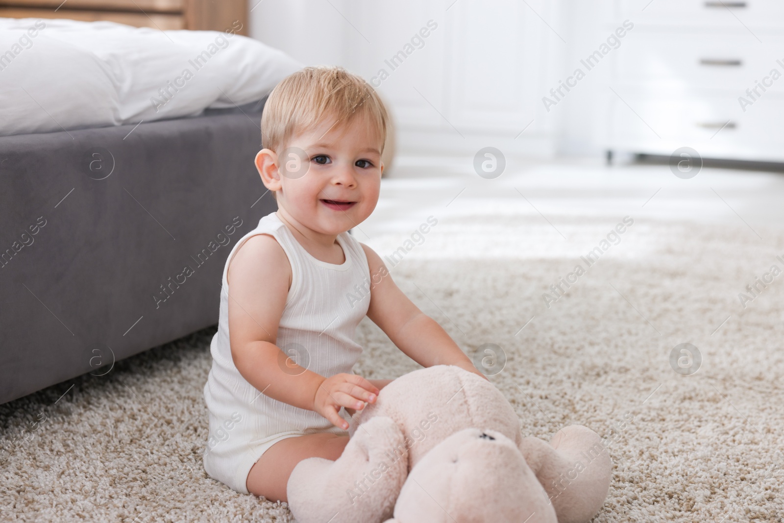 Cute little baby with toy on floor at home Photo of Cute little baby with toy on floor at home