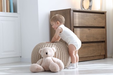 Photo of Cute little baby near pouf at home