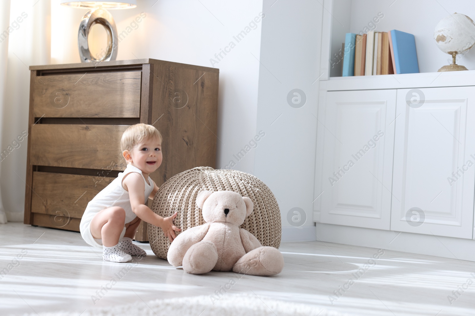 Photo of Cute little baby near pouf at home