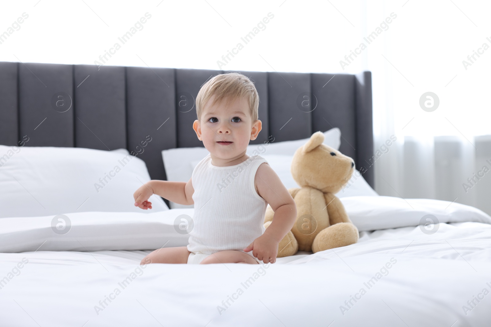Photo of Cute little baby and toy on bed at home