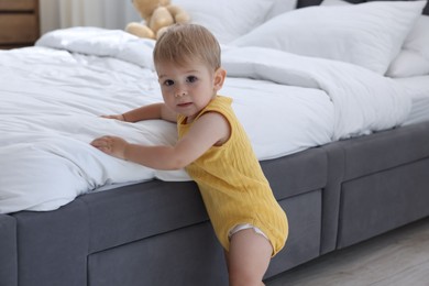 Photo of Cute little baby near bed at home