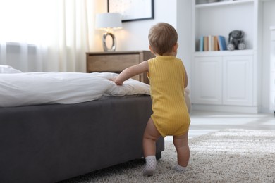 Photo of Cute little baby near bed at home