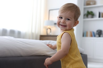 Photo of Cute little baby near bed at home