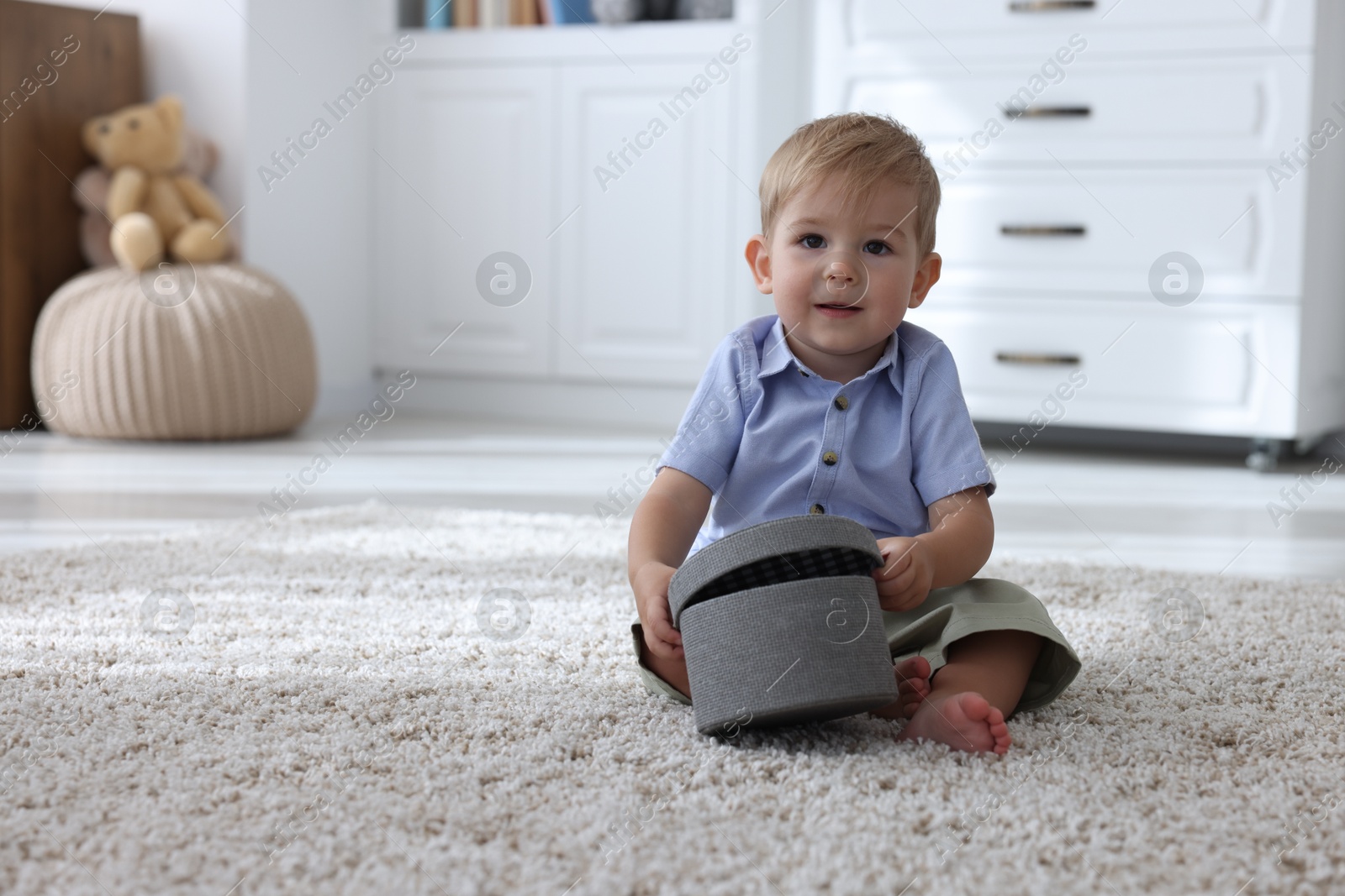 Cute little baby with decorative box on floor at home, space for text Photo of Cute little baby with decorative box on floor at home, space for text