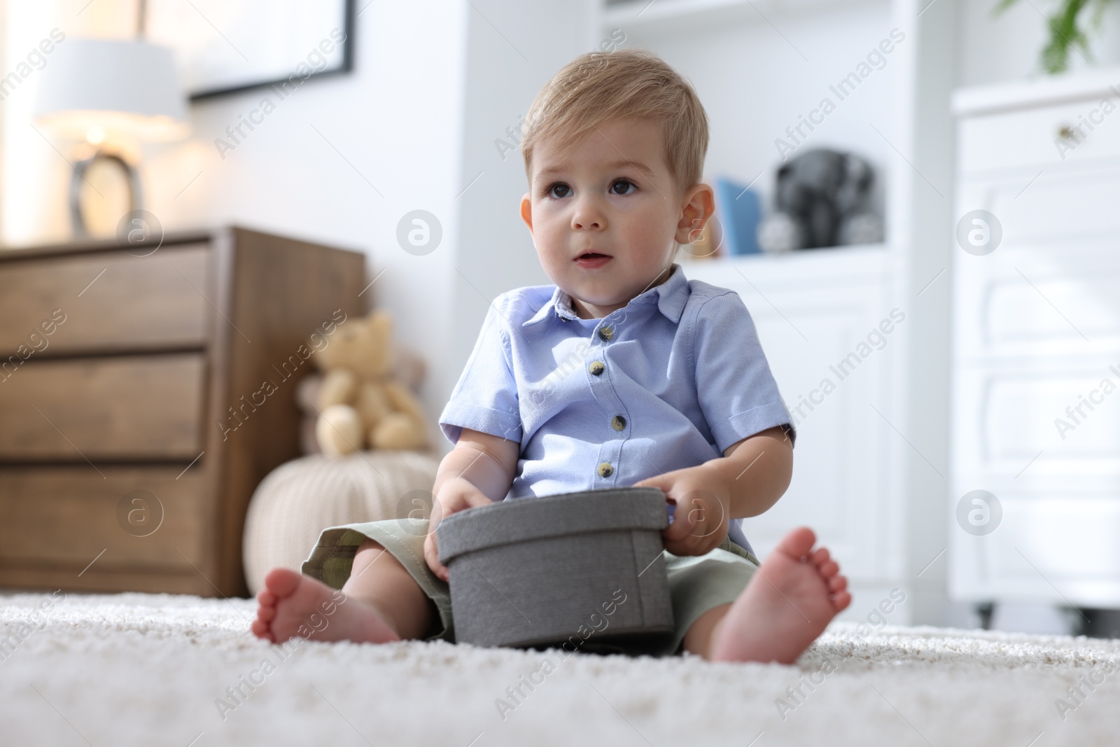 Photo of Cute little baby with decorative box on floor at home