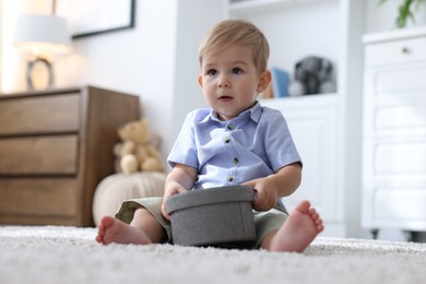 Photo of Cute little baby with decorative box on floor at home