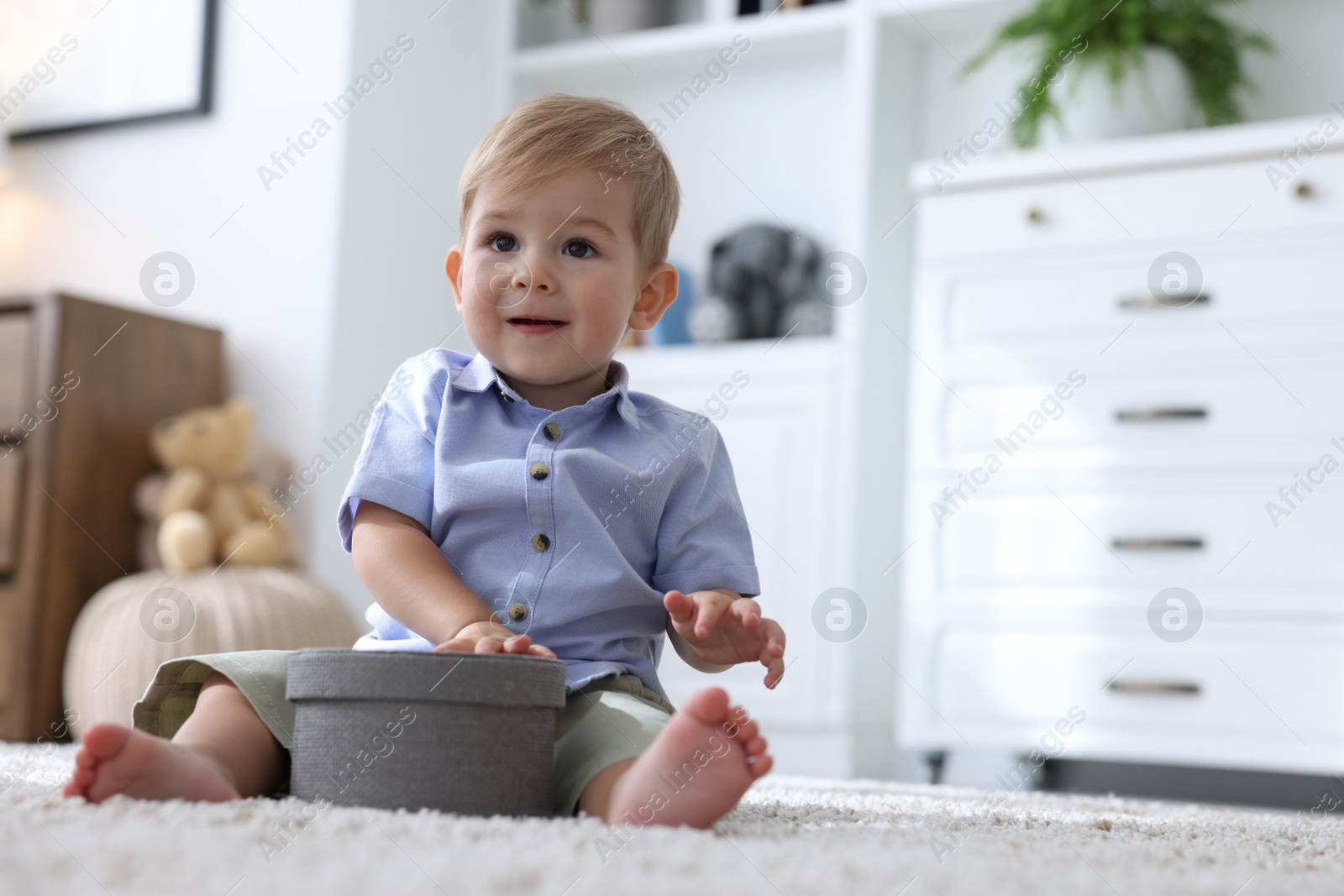 Cute little baby with decorative box on floor at home, space for text Photo of Cute little baby with decorative box on floor at home, space for text